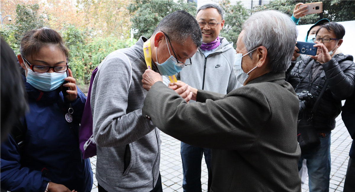 南京大屠殺幸存者艾義英為第一位到達(dá)終點(diǎn)的市民陶成發(fā)頒發(fā)和平紀(jì)念牌。